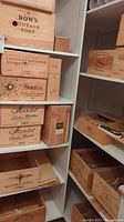 Wooden wine crates stacked on shelves showing different winery labels and vintages.