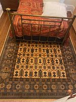 Rug positioned under brass bed frame showing scale and main field pattern