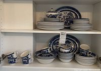 Full cabinet view showing stacks of plates, cups, bowls, tureen and platters