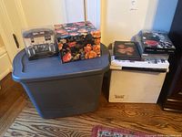 Wide photo of all items: decorative boxes, several boxes of CDs and LPs arranged on floor.