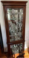 Front view of the dark wood curio cabinet with glass door and visible contents (contents not included).