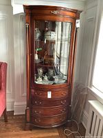 Full front view of curio cabinet showing overall design, curved glass door, and drawer arrangement