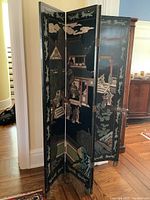 Front and side view of four panel folding room divider showing painted Asian architectural and figurative scenes on black background with decorative borders.