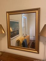 Front view of the full mirror showing frame and reflection of a lamp and furniture.