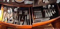 Drawer view showing assorted spoons and forks in felt-lined tray
