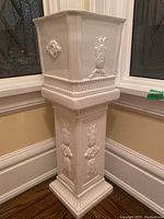 Side view of planter and pedestal stand with floral and rope relief details
