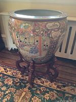 Front view of painted porcelain planter on carved wood stand