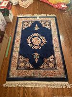 Full top-down view of one navy blue rug showing central medallion, border, and fringed ends