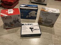 Overview of the four boxed kitchen appliances: Kleva Sumo Slicer, Black & Decker Hand Mixer, Baigelong Hand Mixer, Living Peacock Corkscrew