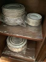 Stack of large dinner plates and medium salad plates on a wooden shelf