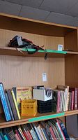 Wide shot of bookshelf with various hardcover and softcover books, a Bugs Bunny comic, and small crates on the shelf.
