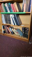 Wide view of wooden shelf showing mixed hardcover and softcover books