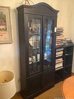 Full front view of cabinet showing arched top, upper glass doors and lower solid doors