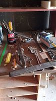 Assorted hand tools including pipe wrenches, screwdrivers, chisels on wooden surface