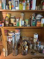 Overall view of shelving unit with various glue bottles, adhesive products, and paint brushes organized in jars and containers.