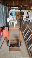Front view of the hand cart dolly showing orange frame, black handle, flat steel base and two large black wheels.