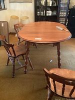 Krogher oval solid maple kitchen table with turned legs and three maple chairs with spindle backs around it.