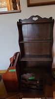 Front view of the four-tier wooden shelf with curved sides, showing engraved detail and the accompanying wooden magazine rack and mail holder on the left and bottom front respectively.