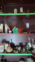 Photo of shelves containing stone bookends, ceramic jars, wooden box and various bottles and silver items