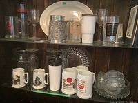 Full shelf view showing various glassware including mugs, glasses, and serving bowls.