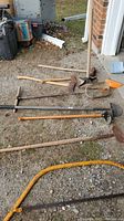 Group of seven assorted tools laid on the ground showing overall condition and variety