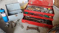 Photo showing red Craftsman toolbox filled with assorted hand tools and the blue propane torch beside it, plus other loose tools and parts on the floor.