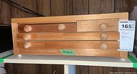 Wooden drawer with four drawers and round wooden pull knobs, dimensions 17x8x7 inches marked on drawer, ticket label visible.