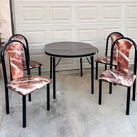 Black formica dining table with gold accents and four matching chairs with patterned upholstery