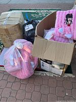 Box with 24 units of pink decorative pillows, some loose pillows visible and bags labeled "Hot Pink" and "Light Pink"