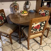 Wooden dining table with 4 floral upholstered chairs arranged around it showing the set up and materials