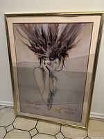 Front view of framed lithograph showing the flapper girl with a large feathered mask and cracked glass.