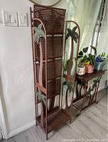 Side view of the tall folding shelf with palm tree decorations and lattice metalwork, showing shelf tiers and fold-flat feature.
