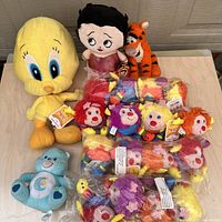 Photo of nine plush toys including Tweety Bird, Betty Boop, Care Bear, and Rainbow Brite sprites on a table.