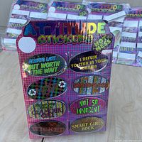 Front view of one package displaying 24 colorful holographic attitude stickers with various phrases.