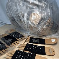 Photo showing multiple black fingerless gloves on wooden hands inside a clear plastic bag, decorated with studs and rhinestones in various patterns.