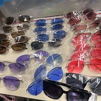 Front view of multiple sunglasses in plastic wrapping, showing various colors and frame styles.