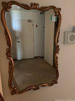 Front view of the ornate gold frame mirror showcasing its overall shape and carvings.