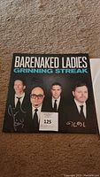Front cover of Barenaked Ladies 'Grinning Streak' vinyl signed by the band members shown wearing suits, signatures visible.