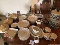 Full set of scattered rose porcelain dinnerware items arranged on table, showing multiple plates, bowls, cups, creamers, gravy boat and platters