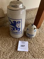 Photo showing Lowenbrau beer stein with blue lion logo and Develey mustard pot on carpet.