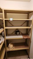 Photo front view of five-shelf metal shelving unit with beige/yellow finish, showing full height and width with some items on lower shelves.