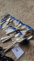 Photo showing multiple silverplated forks and spoons of various sizes laid out on a cloth.
