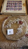 Clear glass cake plate with pink and red floral and berry design, shown next to original box with picture of the plate on it.