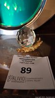 Front view of the vintage gold plated snail figurine holding a clear multifaceted crystal ball on its back, displayed on a flat surface.