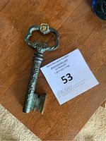 Photo showing vintage metal corkscrew and bottle opener with a decorative handle and patina.