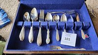 Full view of the incomplete WM Rogers flatware set showing spoons and forks in a blue felt storage box