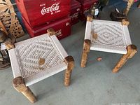 Two artisan rustic woven seats with square woven fabric seat tops and carved wooden legs.