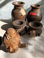 Photo showing two wood vases paired with two circular wooden candle holders and the carved wooden Buddha head in front under natural light.