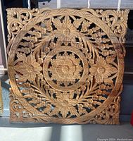 Full front view of the carved wood wall art panel showing circular floral and leaf patterns within a rounded square frame.