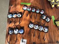 Full view of five sets of metal wall hooks with ceramic hand-painted cabochon inlays, displaying varied numbers of hooks from 2 to 5, showing the colorful geometric and floral paint patterns on each ceramic dome.